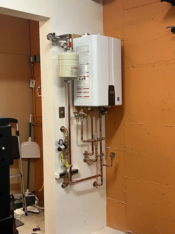 Plumbing technician inspecting water heater connections in Alma